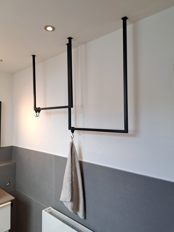 Detailansicht Handtuchhänger aus rechteckigem Rohr in matt schwarz, hängen versetzt über der Heizung.